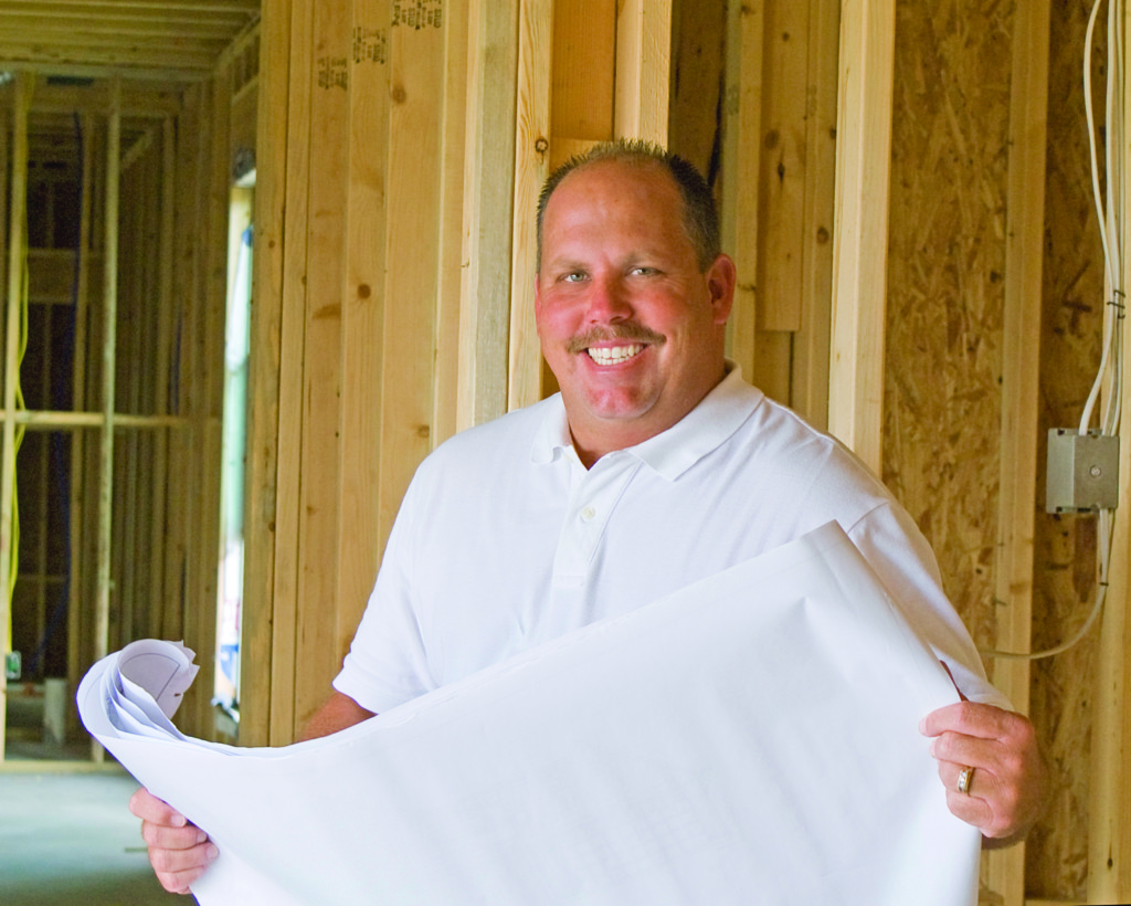 Steve Rabalais holding building blueprint and smiling